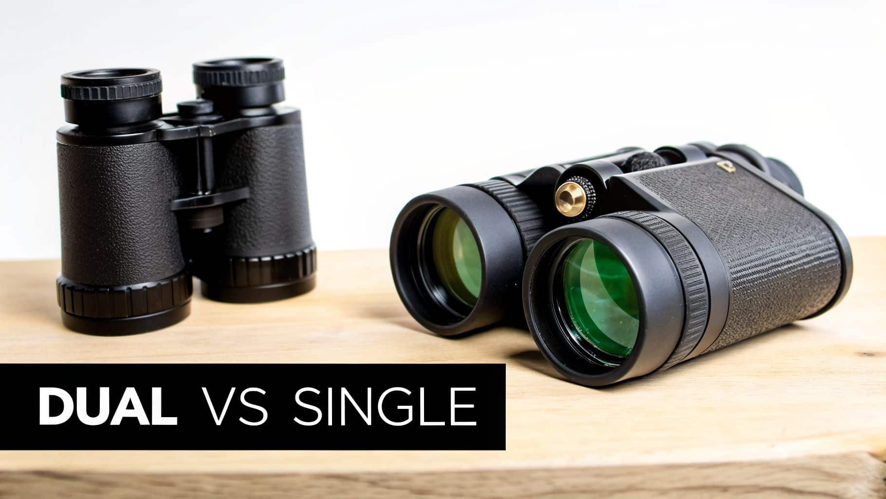 Two black binoculars with green lenses, showcasing different configurations on a wooden surface.