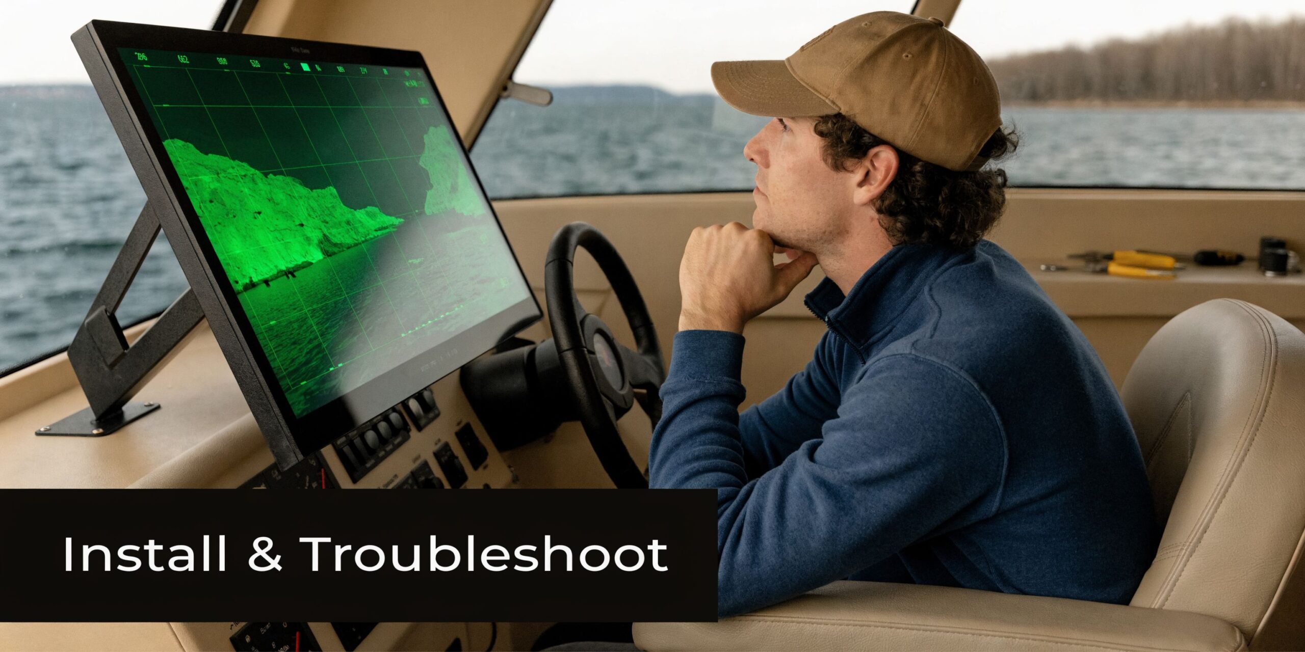 A man wearing a hat sits in a boat captain chair looking at a digital radar screen.