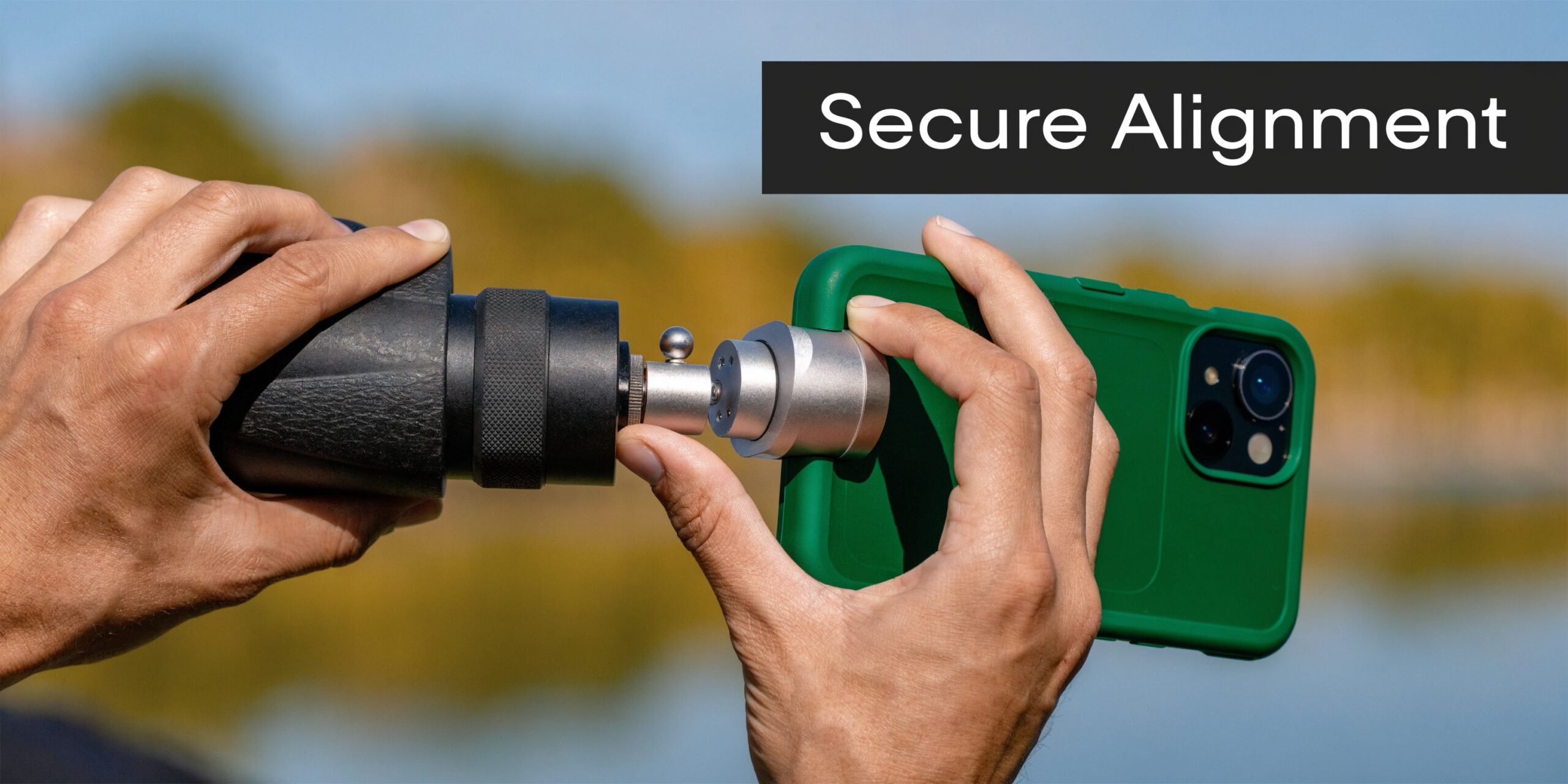 A person aligning a smartphone with a green case to a monocular using a specialized metal adapter.